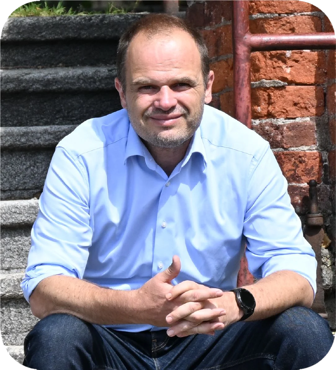 Michal Šmarda sedí na schodech před cihlovou budovou